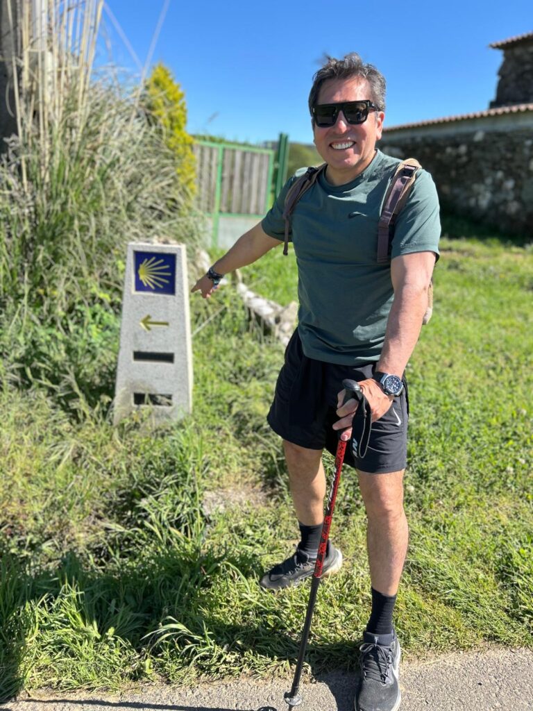 Pedro Cortez en una caminata al aire libre, sonriendo y señalando durante una actividad de hiking